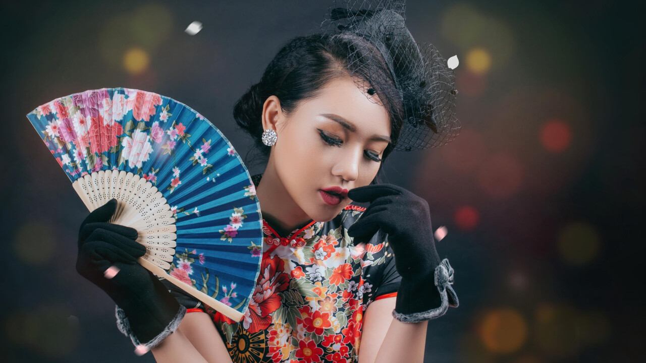Престарелая азиатская гейша с веером в руках дает интервью